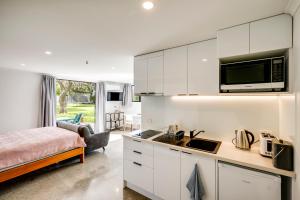 a kitchen with white cabinets and a bed in a room at Modern Studio near Clive River in Clive