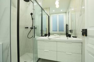 a white bathroom with a shower and a sink at Résidence Opéra by Studio prestige in Paris