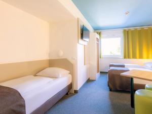 una camera d'albergo con due letti e un tavolo di B&B Hotel Stuttgart-City a Stoccarda Altre 21 foto