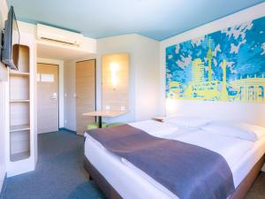 1 dormitorio con 1 cama con una pintura en la pared en B&B Hotel Stuttgart-City en Stuttgart