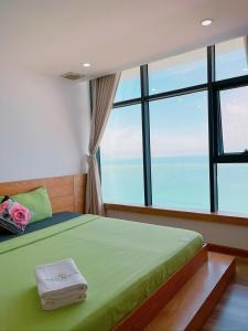 Schlafzimmer mit einem grünen Bett und einem großen Fenster in der Unterkunft Pearl Nha Trang Beach Apartment in Nha Trang
