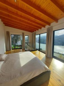 a bedroom with a large bed with large windows at Quinta Vale do Cabo in Riba Douro