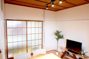 sala de estar con TV, mesa y sillas en Daiichi Mitsumi Corporation - Vacation STAY 15393, en Musashino