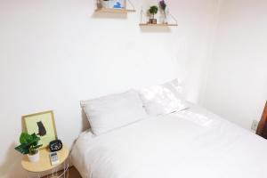 1 dormitorio con cama blanca y mesa auxiliar en Daiichi Mitsumi Corporation - Vacation STAY 15393, en Musashino