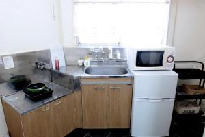 una pequeña cocina con fregadero y microondas en Daiichi Mitsumi Corporation - Vacation STAY 15266, en Musashino