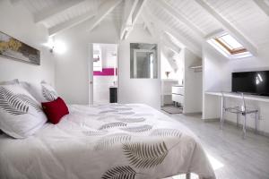 a white bedroom with a large bed with a red pillow at VILLA L'INDIA - Un havre de paix familiale in Labarthe +16 photos