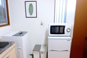 a kitchen with a microwave on top of a refrigerator at Daiichi Mitsumi Corporation - Vacation STAY 15356 in Musashino