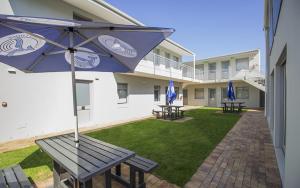 - une terrasse avec 2 tables de pique-nique et un parasol dans l'établissement Kleinmond Lodge, à Kleinmond