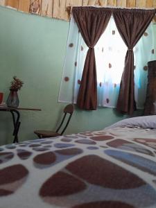 1 dormitorio con 1 cama y una ventana con cortinas en Cozy Huts, en Nyandarua 