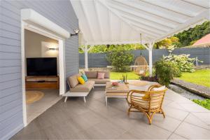 a patio with a couch and a table at Villa Paisible, proche de la Soufrière in Gourbeyre