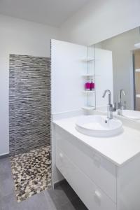 La salle de bains blanche est pourvue d'un lavabo et d'un miroir. dans l'établissement Les VILLAS AZULIA, à Saint-François