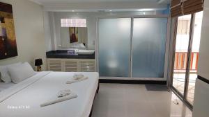 1 dormitorio con 1 cama blanca grande y baño en Siam Palm Residence en Patong