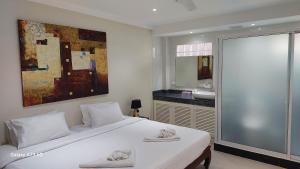 um quarto com uma grande cama branca e uma casa de banho em Siam Palm Residence em Praia de Patong