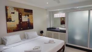 a bedroom with a large white bed and a bathroom at Siam Palm Residence in Patong Beach