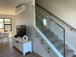 uma escada com corrimão de vidro numa sala de estar em Northshore Charming 4 bedrooms em Auckland