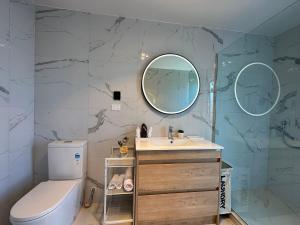 a bathroom with a sink and a toilet and a mirror at Northshore Charming 4 bedrooms in Auckland