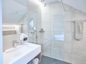a white bathroom with a sink and a shower at Hotel Balga in Balgach