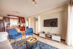 un soggiorno con divano, sedie e TV di Beachfront 3rd floor 2 bedroom w communal swimming pool- B16 Blouberg a Bloubergstrand