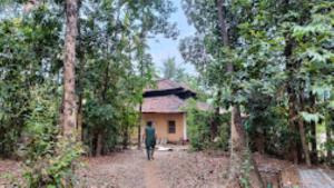 a man walking down a dirt road in front of a house at Vanoshi Forest Homestay,Kudase in Maneri