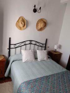 Casa Harillo-Charming 1 bedroom in Genal mountains في خينالغواثيل: غرفة نوم مع سرير مع قبعتين على الحائط
