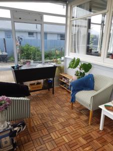 a living room with a piano and two chairs at Minimalist Cabin Solo Traveller in Ashburton
