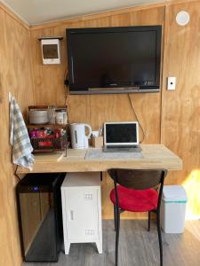 a desk with a laptop and a tv on a wall at Minimalist Cabin Solo Traveller in Ashburton