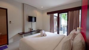a bedroom with a white bed with a teddy bear on it at The Lavana Bali Radiance Villa Canggu in Canggu