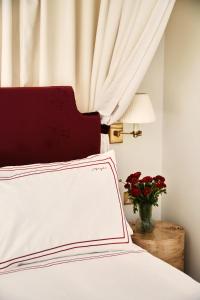 een wit bed met een rood hoofdeinde en een vaas met bloemen bij Magda Boutique Rooms in Londen