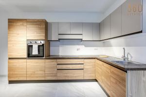 een keuken met houten kasten en een wastafel bij Modern 2BR Apt with Private Terrace & Sofa Bed by 360 Estates in St Paul's Bay