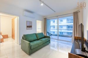 een woonkamer met een groene bank en een groot raam bij Modern 2BR Apt with Private Terrace & Sofa Bed by 360 Estates in St Paul's Bay