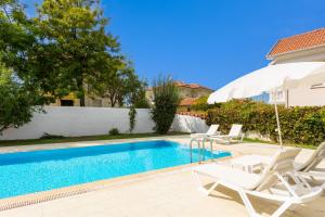 a swimming pool with two lawn chairs and an umbrella at Villa Oliv in Oludeniz