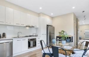 a kitchen with white cabinets and a table and chairs at BeachTownhouse779 in Rosebud