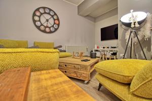 sala de estar con sofá, mesa y reloj en Aux grains de raisin - 6 personnes - cour privée en Scherwiller