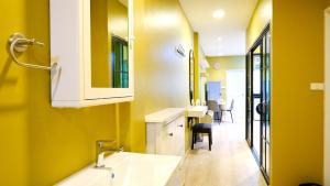 een badkamer met een wastafel en een gele muur bij BEB Silom Condolette in Bangkok +11 foto's