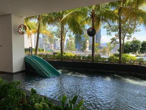 a water slide in a pool with palm trees at Greystone Continew Residensi in Kuala Lumpur