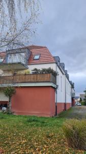 een wit en oranje gebouw met een balkon bij Logement entier : appartement, Houssen in Houssen