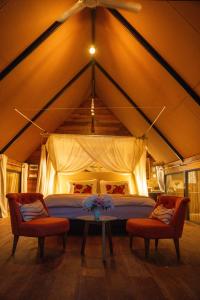 a bedroom in a tent with a bed and two chairs at Treellion Jungloo in Phnom Penh