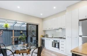 a kitchen with white cabinets and a glass table at BeachTownhouse779 in Rosebud