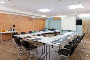 een vergaderzaal met tafels en stoelen en een whiteboard bij Hotel Residence Les Medes in Porquerolles