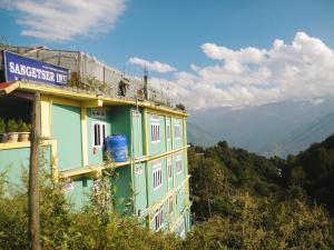 a green building with a sign on the side of it at Shungatser inn in Tawang