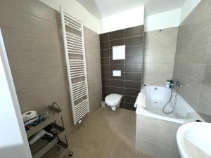 a bathroom with a toilet and a tub and a sink at Sky Apartments 502 in Plzeň