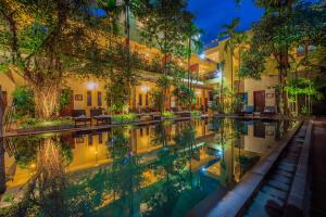 a pool in the courtyard of a building at night at Samnak Lounge in Siem Reap