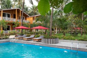 a resort with a swimming pool with chairs and umbrellas at Aralea Beach Resort By Stone Wood Premier in Morjim