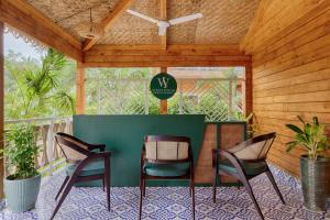 a patio with three chairs and a table with a sign at Aralea Beach Resort By Stone Wood, Morjim in Morjim