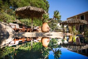 uma piscina com cadeiras e guarda-sóis ao lado de um resort em Hotel Residence Les Medes em Porquerolles