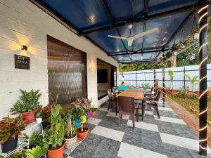 a patio with a table and chairs and potted plants at Cloud9 Villa (Yeoor Hills, Thane) - A Luxurious Private Jungle Villa. in Thane