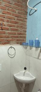 een badkamer met een witte wastafel en een bakstenen muur bij Aconchego Santa Luzia in Pirenópolis