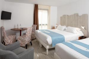 um quarto de hotel com duas camas e uma mesa e cadeiras em Hotel Residence Les Medes em Porquerolles
