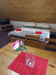 Chata Dáša في كورينوف: طاولة مع إناء من الزهور على طاولة مع سرير