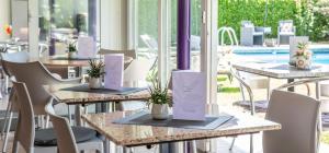 Smart-HOTEL MINUSIO, a Benvenuti Hotel في لوكارنو: صف طاولات عليها نباتات في مطعم